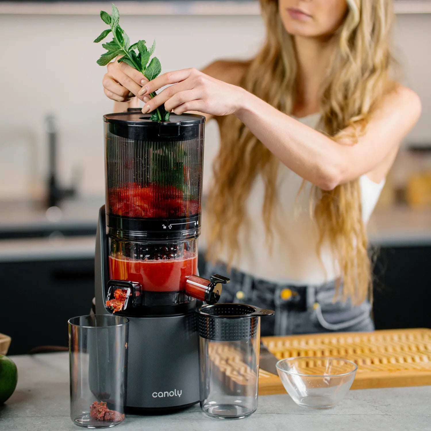 Canoly C16 cold press masticating juicer processing greens and tomatoes, with dry pulp ejection and slow extraction, grey